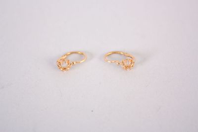 une paire de boucles d'oreilles en or sur une surface blanche