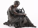 bronze statue of a woman sitting on a bench with a vase in her lap