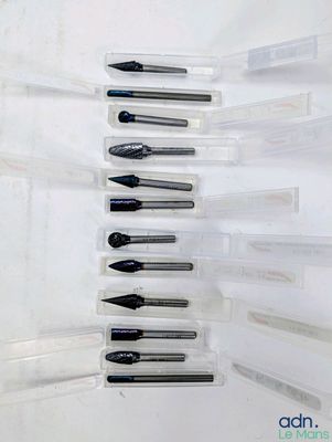 Plusieurs stylos sont alignés en rang sur une surface blanche.