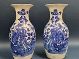 pair of blue and white vases with figures on them