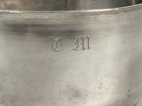 a silver bowl with a spoon in it on a white surface