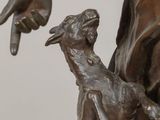 bronze statue of a woman holding a dog and pointing at it