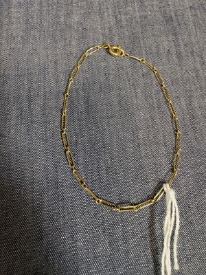 un bracelet en chaîne d'or auquel pend un pompon