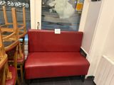 un canapé rouge placé devant une fenêtre dans une pièce