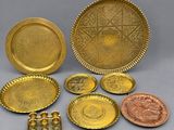 several different types of brass plates and trays on a gray surface