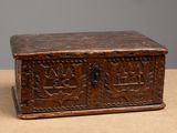 an old wooden box with carvings on it sitting on top of a table