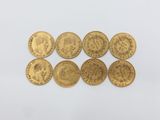 a group of six gold sovereigns on a white surface