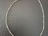 a silver chain bracelet with a heart charm on a black leather surface
