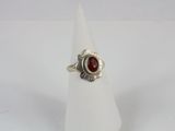 a close up of a silver ring with a red stone in it