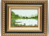 a painting of a lake with trees and bushes in a gold frame