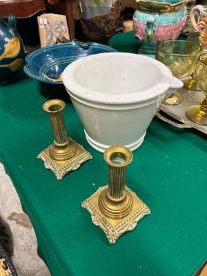 une table verte sur laquelle sont posés un bol blanc et des bougeoirs dorés