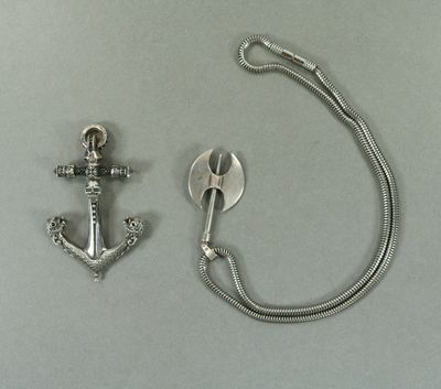 une ancre en argent et une cuillère en argent posées sur une table
