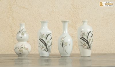 quatre vases posés sur une table, avec un mur en arrière-plan