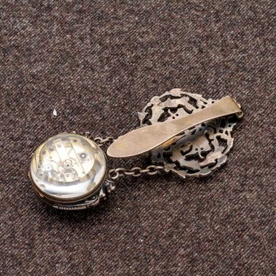 une pince à cravate en argent sur laquelle est fixée une montre de poche
