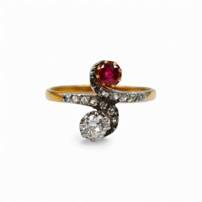 a close up of a gold ring with a red stone and diamonds