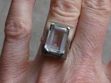 a person ' s hand holding a ring with a clear stone on it