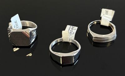 trois bagues en argent ornées d'étiquettes, posées sur une surface noire