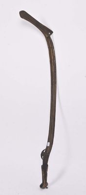 a small metal object with a long handle on a white surface