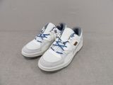 des baskets blanches avec des lacets bleus, posées sur une surface grise
