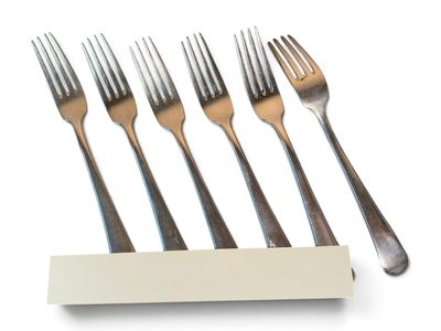 four forks and a napkin on a white table