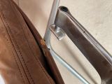 a close up of a brown leather bag on a chair