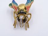 an image of a gold and enamel insect broochle on a white surface