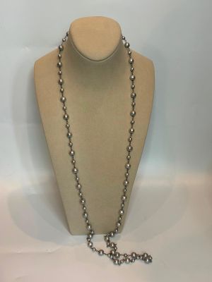 collier de perles argentées orné d'une croix, présenté sur un mannequin