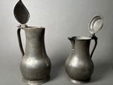 two silver vases sitting next to each other on a table