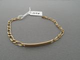 a close up of a gold chain bracelet with a tag on it