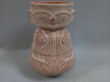 a small vase with a face on it on a table