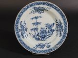 blue and white plate with flowers and birds on it on a black surface