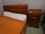 a bed that has a pillow on it next to a night stand