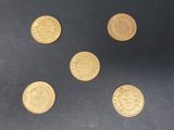 six pièces d'or empilées les unes sur les autres sur une surface noire