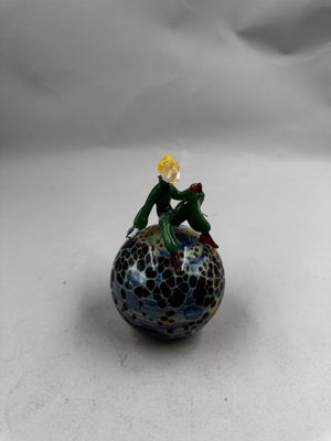 petite figurine en verre représentant une grenouille assise sur une balle
