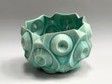 a green bowl with a design on it on a white surface