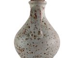 un petit vase blanc parsemé de taches marron