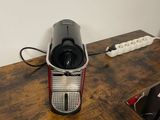 a coffee maker sitting on a wooden table next to a wall