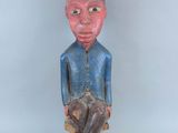 une vieille statue en bois d'un homme avec un chapeau sur la tête