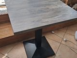 a square table with a metal base on a tiled floor