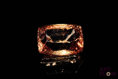 un gros plan d'une bague ornée d'un diamant orange sur un fond noir