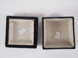 pair of black and white porcelain boxes with labels on them