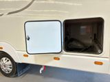 a small white trailer with a door open in a garage