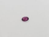 a pink sapphire stone on a white surface