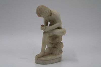 statue représentant un homme assis sur un rocher, les mains posées sur les genoux