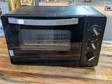 un four grille-pain noir posé sur une table en bois