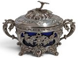 an antique silver and blue glass covered dish with a bird on top