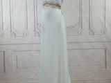 the dress is white and has a gold belt on the waist