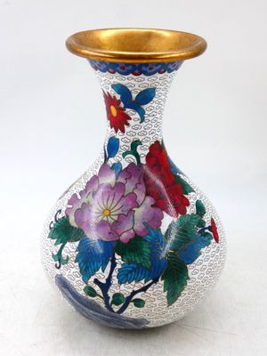 un vase avec des fleurs peintes dessus, posé sur une table