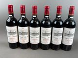 six bottles of red wine lined up in a row