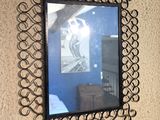 a mirror hanging on the wall with a picture in it